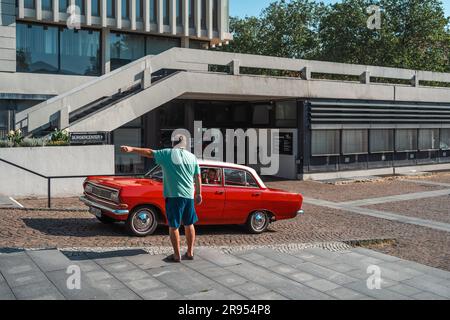 Kaiserslautern, Germania. 24 giugno 2023. L'organizzatore dà indicazioni mentre un rosso 1965 Opel Rekord B arriva a Willy-Brandt-Platz (piazza) per partecipare all'evento rallye. Il 15° Kaiserslautern Classics combina una mostra di auto d'epoca con l'ex ADAC Trifels Historic rallye (ora sotto il nuovo nome "ADAC Trifels Oldtimerwanderung") e una riunione in Vespa. L'evento inizia il sabato alle 8:30 e prosegue in varie località pubbliche del centro città per tutto il giorno, accompagnato da band di musica dal vivo. Credito: Gustav Zygmund/Alamy News Foto Stock