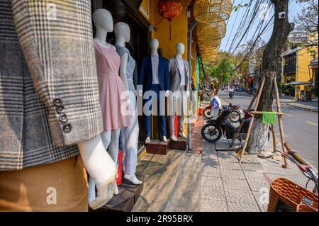 Manichini vestiti in piedi vicino all'ingresso dei sarti Ba-Ri nella città vecchia di Hoi An, Vietnam. Foto Stock