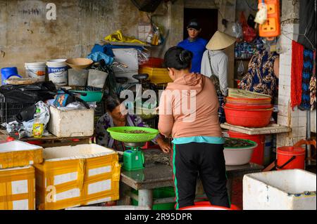 Un venditore pesa i gamberi per un acquirente locale nel mercato del pesce al mercato di Hoi An nella città vecchia di Hoi An, in Vietnam. Foto Stock