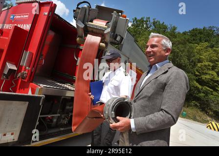 24 giugno 2023, Baden-Württemberg, Külsheim: Thomas Strobl, ministro dell'interno del Baden-Württemberg, (CDU) tiene una manichetta antincendio durante un'esercitazione antincendio con 400 personale di emergenza in un'area di addestramento della Bundeswehr. Foto: Karl-Josef Hildenbrand/dpa Foto Stock