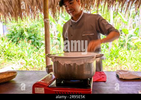 Chef e tutor dimostrano come cucinare la carta di riso utilizzata per panini e spaghetti presso la scuola di cucina Red Bridge alla periferia di Hoi An, in Vietnam. Foto Stock