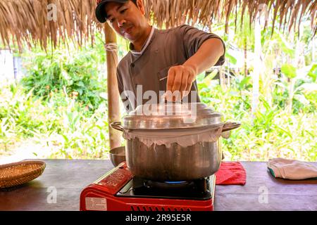 Chef e tutor dimostrano come cucinare la carta di riso utilizzata per panini e spaghetti presso la scuola di cucina Red Bridge alla periferia di Hoi An, in Vietnam. Foto Stock