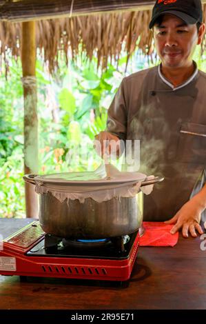 Chef e tutor dimostrano come cucinare la carta di riso utilizzata per panini e spaghetti presso la scuola di cucina Red Bridge alla periferia di Hoi An, in Vietnam. Foto Stock