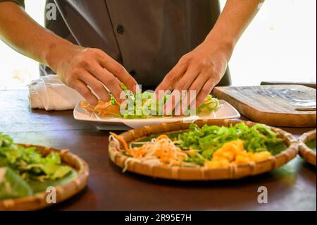 Chef e tutor dimostrano come preparare rotoli di carta di riso fresco con gamberi alla Red Bridge Cooking School, alla periferia di Hoi An, Vietnam. Foto Stock