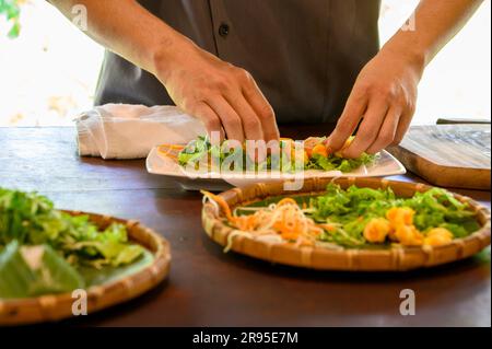 Chef e tutor dimostrano come preparare rotoli di carta di riso fresco con gamberi alla Red Bridge Cooking School, alla periferia di Hoi An, Vietnam. Foto Stock