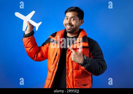 Un giovane che punta il dito verso l'aereo per tagliare la carta con un sorriso toothy Foto Stock