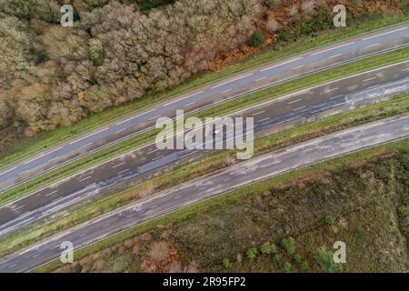 Da una prospettiva aerea, un'auto che viaggia lungo una strada panoramica e tortuosa attraverso una foresta Foto Stock