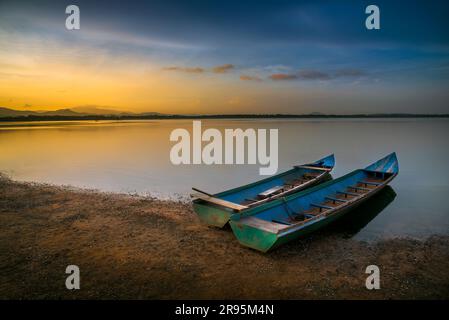 Barche nel serbatoio al crepuscolo con cielo colorato in Thailandia Foto Stock