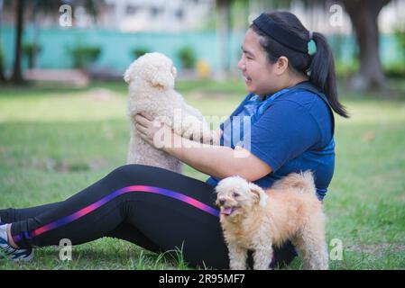 Giovane donna cinese all'aperto nel paesaggio del parco pubblico e che tiene in braccio il cane Foto Stock