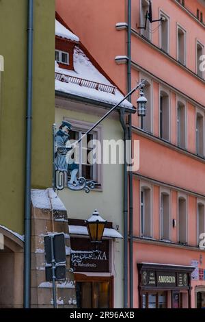 Klodzko, Polonia - gennaio 2023: Lampada appesa su un cartello di metallo della città a forma di uomo con lanterna sulle strade della città Foto Stock