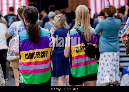 Charlotte, North Carolina, USA. 24 giugno 2023. Le donne che indossano i giubbotti di scorta della clinica ascoltano gli oratori prima che il vicepresidente degli Stati Uniti Kamala Harris parli in occasione del primo anniversario della decisione della suprema Courts Dobbs degli Stati Uniti al Grady Cole Center di Charlotte, North Carolina, USA, 24 giugno 2023. La sentenza della Corte Suprema degli Stati Uniti nella causa Dobbs contro Jackson Women's Health Organization ha rovesciato il caso storico sui diritti all'aborto di Roe contro Wade. Crediti: Erik S. Lesser/Pool tramite CNP/dpa/Alamy Live News Foto Stock