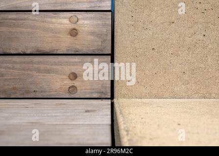 Contrasto di forme e texture, bordo di una panca in legno e seduta in cemento. Foto Stock