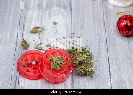 boccioli di marijuana medica e un macinacaffè di plastica rossa Foto Stock