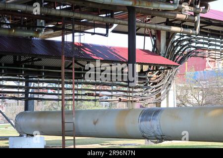 Cavalcavia di tubazioni con tubi arrugginiti in ferro per pompare liquidi, condensa con uscite e scarichi in raffineria di petrolio, petrolchimica, impianti chimici contro Foto Stock