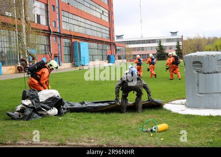 Vigili del fuoco professionisti, soccorritori in tute di protezione antincendio, caschi bianchi e maschere antigas si stanno preparando a salvare le persone dal bullo industriale Foto Stock