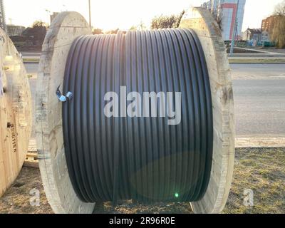 Grandi bobine rotonde in legno di bobine con fili, cavi elettrici neri in isolamento in gomma, utilizzati nel cablaggio di linee di conduttori in impianti industriali Foto Stock