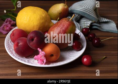 Albicocche fresche limoni pere e ciliegie dolci sul piatto bianco Foto Stock