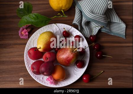 Albicocche fresche limoni pere e ciliegie dolci sul piatto bianco Foto Stock