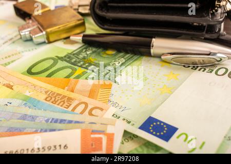 pennarello orologio con borsetta oro più leggero sullo sfondo di banconote da 100 euro a moneta verde Foto Stock