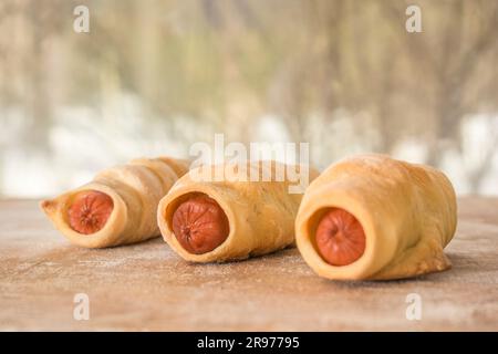 Tre panini con salsiccia si trovano su una lavagna sullo sfondo di una strada invernale Foto Stock