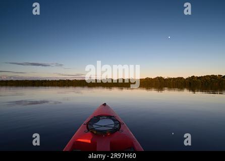 Kayak rosso a Coot Bay nel Parco Nazionale delle Everglades, Florida, con la luna sullo sfondo alla luce del tardo pomeriggio. Foto Stock