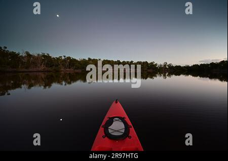 Kayak rosso a Coot Bay nel Parco Nazionale delle Everglades, Florida, con la luna sullo sfondo durante il crepuscolo serale. Foto Stock