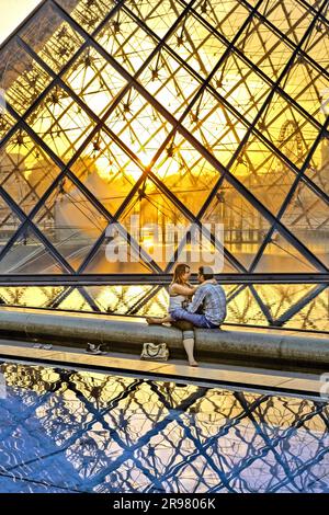 PARIGI, FRANCIA - LUGLIO 07: UN PAIO DI AMANTI SAT DI FRONTE ALLA PIRAMIDE FERITOIA IL 7 LUGLIO 2010 A PARIGI, FRANCIA. Foto Stock