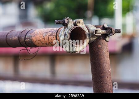 Primo piano dell'accoppiatore del giunto arrugginito per ponteggi metallici, il blocco del ponteggio con morsetto per tubi è resistente nel cantiere. Foto Stock