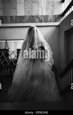 Scena horror di una donna spaventosa in abito bianco in un edificio abbandonato. Concetto spaventoso di Halloween Foto Stock