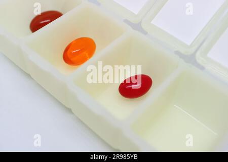 Custodia organizer per pillole giornaliere aperta con pillole integrative assortite isolate su sfondo bianco Foto Stock