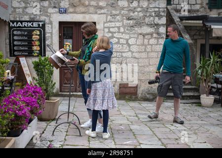 Cattaro, Montenegro, 13 aprile 2023: Un paio di turisti con una figlia che esplorano la città vecchia Foto Stock