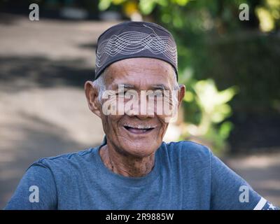 Giacarta, Indonesia - 20 giugno 2023: Ritratto di un uomo anziano asiatico che indossa un cappello nero con capelli grigi sorridenti davanti alla fotocamera Foto Stock