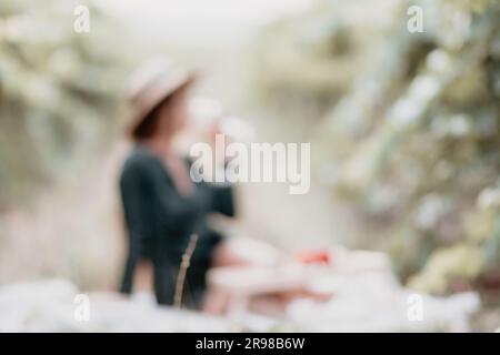 Astratto defocused donna vigneto picnic. Felice donna con un bicchiere di vino in un pic-nic in vigna, degustazione di vini al tramonto e la natura aperta nel Foto Stock
