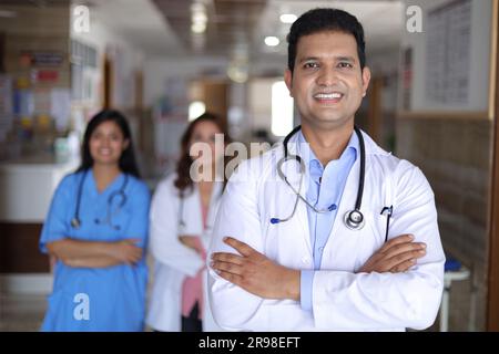 Medico sicuro con un collega in piedi sullo sfondo nel corridoio dell'ospedale. Indossare camice da laboratorio e stetoscopio in clinica privata, team medico che lavora Foto Stock