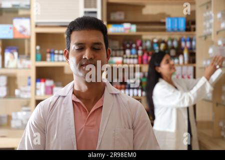 Farmacista chimico indiano uomo in piedi in farmacia - farmacia. Primo piano del farmacista della farmacia dell'ospedale. Farmacista che assiste i clienti Foto Stock