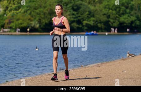 Un visitatore di Hyde Park, Londra, corre lungo il Serpentine. Data foto: Domenica 25 giugno 2023. Foto Stock