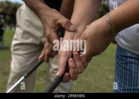 Un primo piano delle mani delle persone su un campo da golf, tenendo un golf club in una mano e gestando Foto Stock