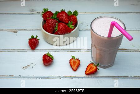 Frullato di fragole, fragole biologiche in un recipiente bianco su sfondo di legno bianco, primo piano. Foto Stock