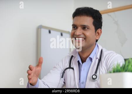 Giovane medico indiano seduto con paziente che ha una conversazione dettagliata. Felice giovane medico sorridente. Concetti del servizio di consulenza. Stetoscopio. Foto Stock