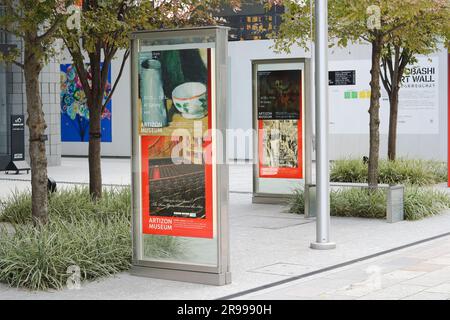 TOKYO, GIAPPONE - 30 ottobre 2022: Cartelli pubblicitari mostre di fronte ad Artizon, un museo d'arte nella zona di Kyobashi a Tokyo. Una recinzione attorno a un costrutto Foto Stock