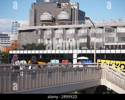 TOKYO, GIAPPONE - 16 giugno 2023: Veduta della passerella pedonale nell'area di Harajuku a Tokyo con un edificio che ospita una mostra Rimowa, 'SEIT 1898'. Foto Stock