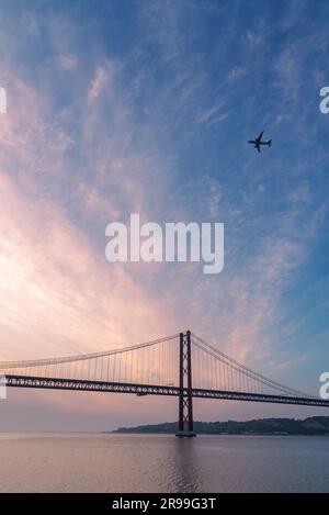 Ponte 25 de Abril all'alba con un aereo che sorvola Lisbona. Foto Stock