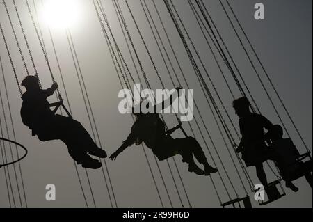 Batumi, Georgia. 24 giugno 2023. I passeggeri si siedono su una giostra a catena e si silhouette sotto la luce del sole. Credito: Sebastian Kahnert/dpa/Alamy Live News Foto Stock