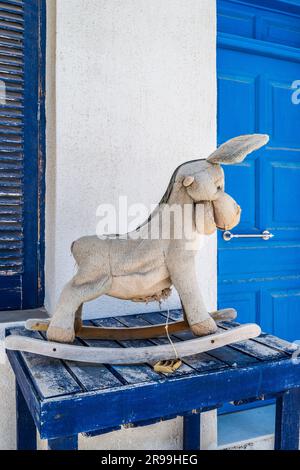 Giocattolo d'asino ripieno abbandonato fuori da una tradizionale casa di villaggio di Apollo, un piccolo villaggio di pescatori a Naxos, in Grecia. Foto Stock