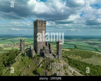 La vista aerea dei resti del castello medievale di Hazmburk con una torre circolare e rettangolare si trova in cima a questo punto di trekking a picco basso con sceni Foto Stock