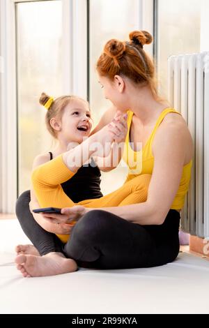 Mamma giovane in forma che guarda amorevolmente sua figlia Foto Stock