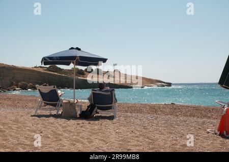 Vista di due turisti sulla spiaggia di Fourni. Sono seduti sul lettino e rilassano il clima caldo. Isola di rodi, Grecia. Foto Stock