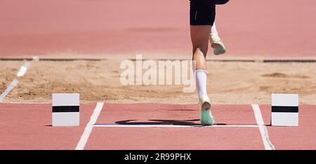 Uomini salto lungo atleta salto in gara di atletica, sportivo che atterra la gamba a bordo prima di decollare in salto lungo o salto triplo Foto Stock