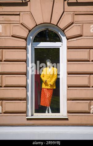 Un manichino vestito da donna si trova nella finestra di una vecchia casa Foto Stock