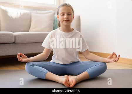 Adolescente caucasica seria in abbigliamento sportivo con meditazione a occhi chiusi, pratica yoga, goditi il relax Foto Stock